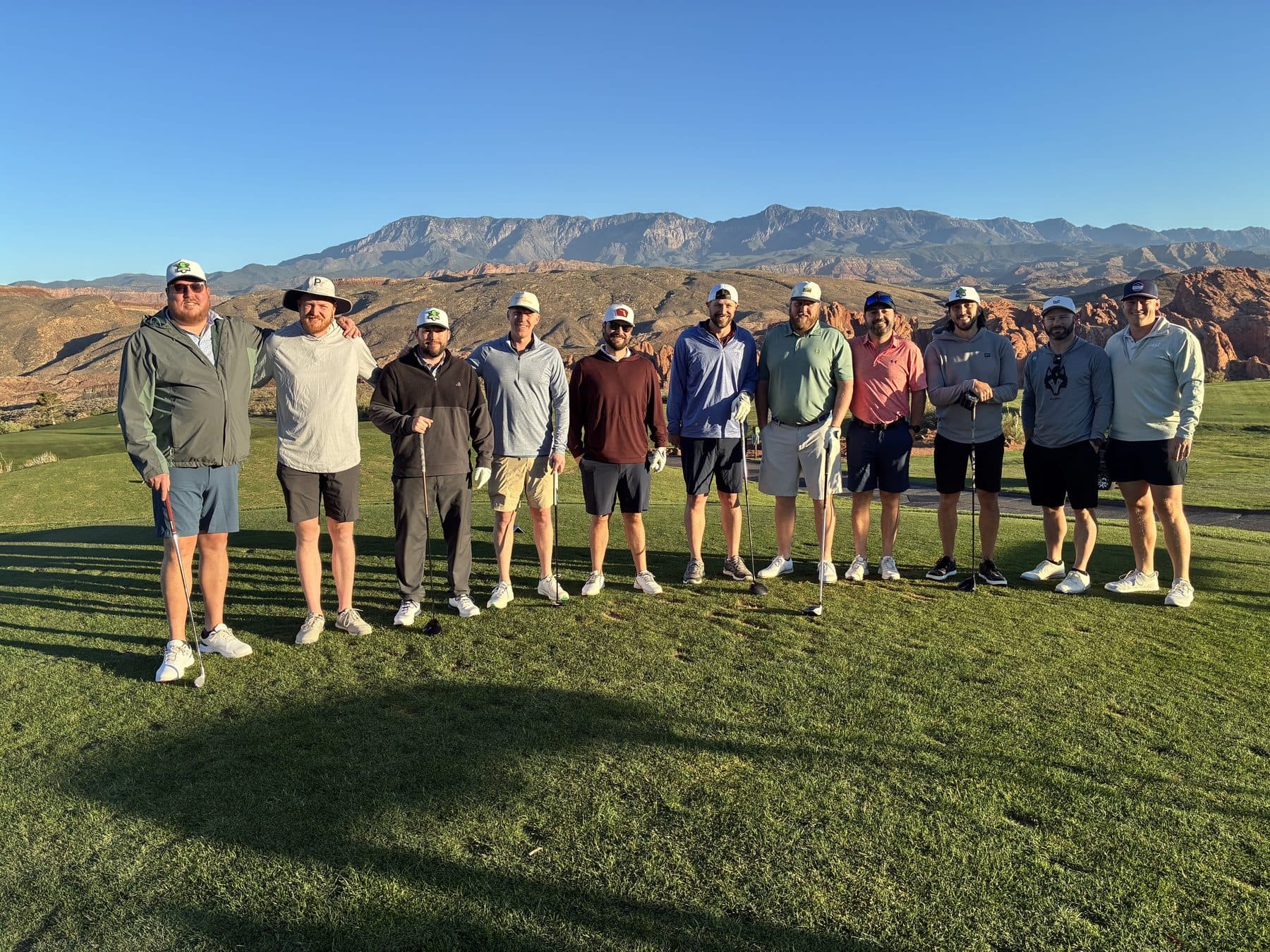 A golf trip group standing together with mountains behind the course.